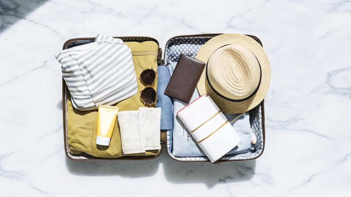 Ceļotāja soma ar tulkojumu grāmatu un turku tējas glāzi uz fona ar bazāra ainavu