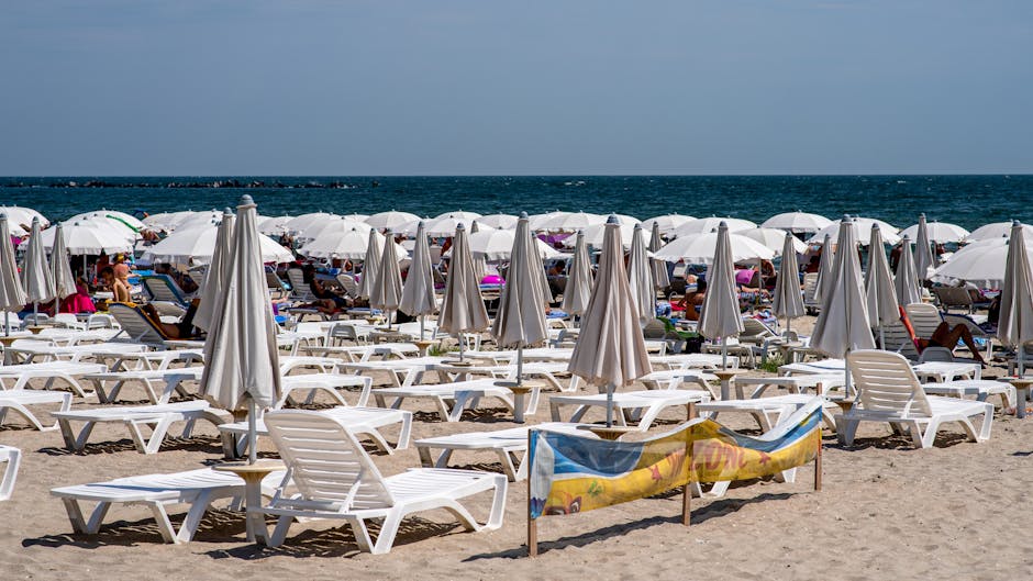 Saulainais krasts — Saulaina pludmale Bulgārijā ar baltiem saulessargiem un atpūtas krēsliem pie Melnās jūras.