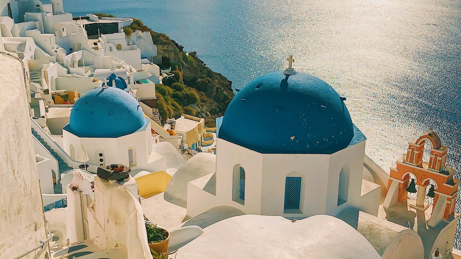 Grieķijas salas baltās mājiņas ar ziliem kupoliem un jūras skatu