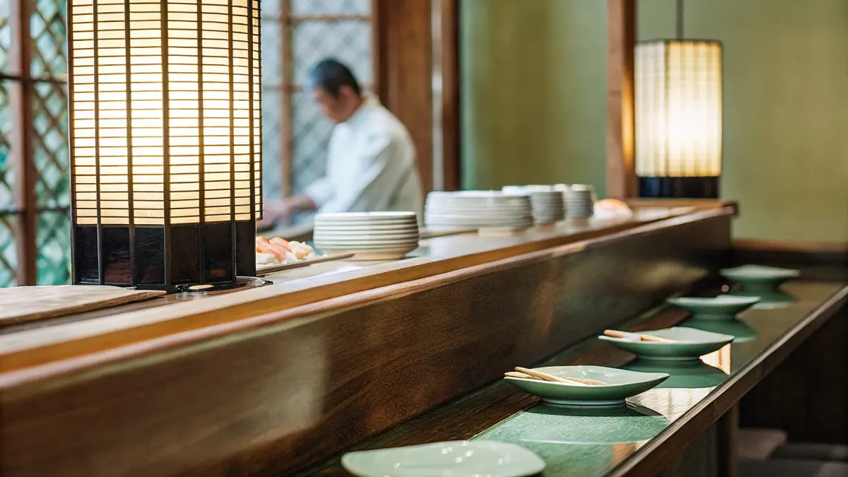 Tradicionāla japāņu restorāna interjers ar koka leti un siltu apgaismojumu