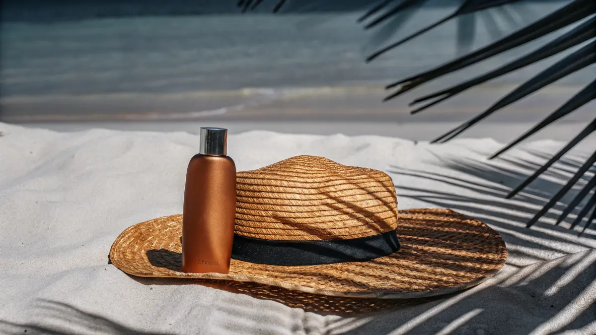 Sauļošanās piederumi un saules aizsargkrēms uz pludmales dvieļa